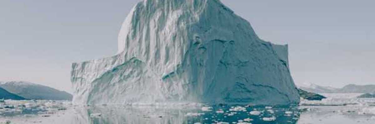 A view of water with a huge iceberg in the distance