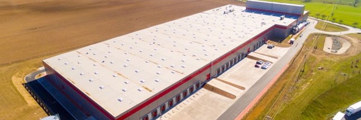 A warehouse or data center sited in the middle of green fields.