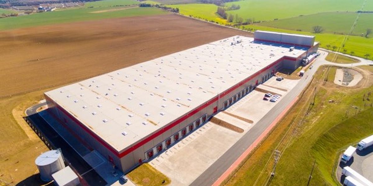 A warehouse or data center sited in the middle of green fields.