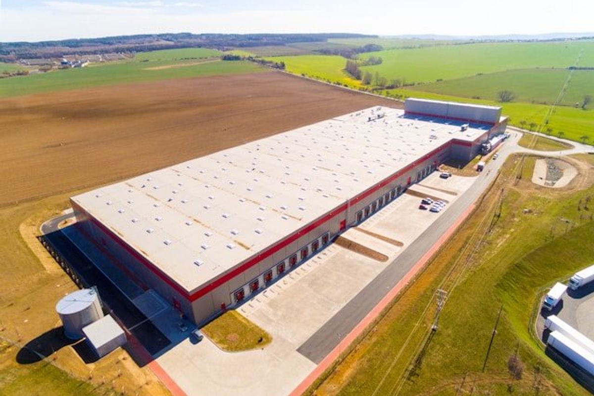 A warehouse or data center sited in the middle of green fields.