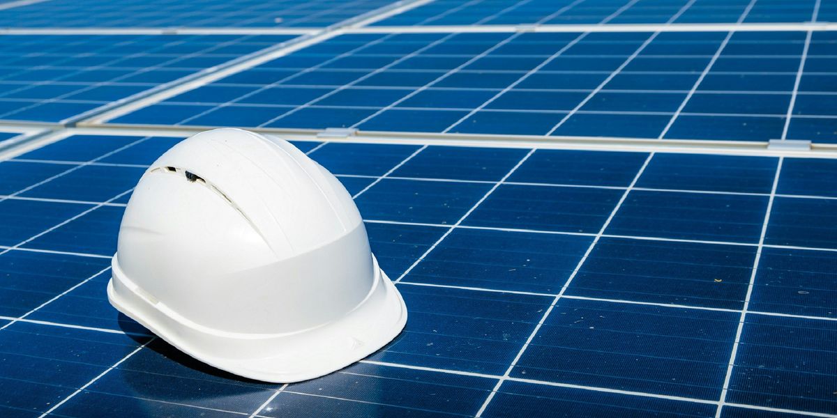 a white hard hat sitting on top of a solar panel.