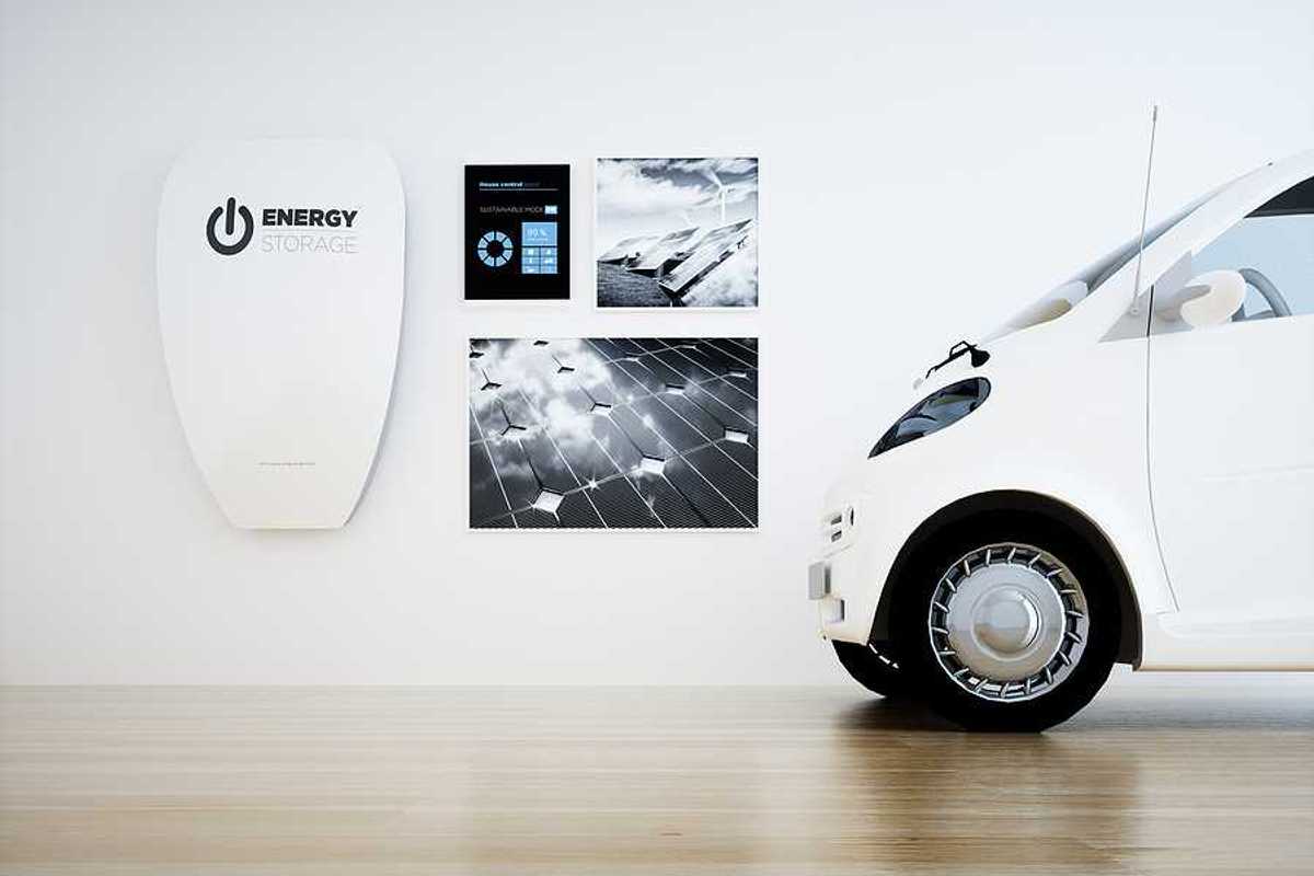 A white home energy battery installed on a wall next to a small white electric vehicle