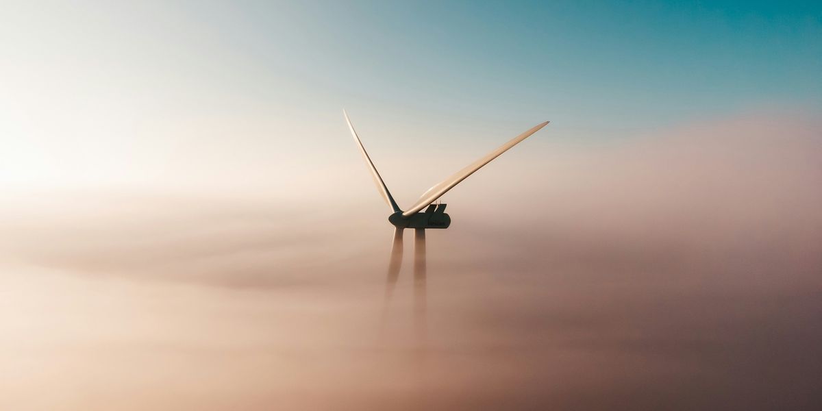 A wind turbine rising above the fog.