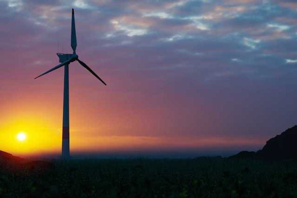 A wind turbine silhouetted against the setting sun