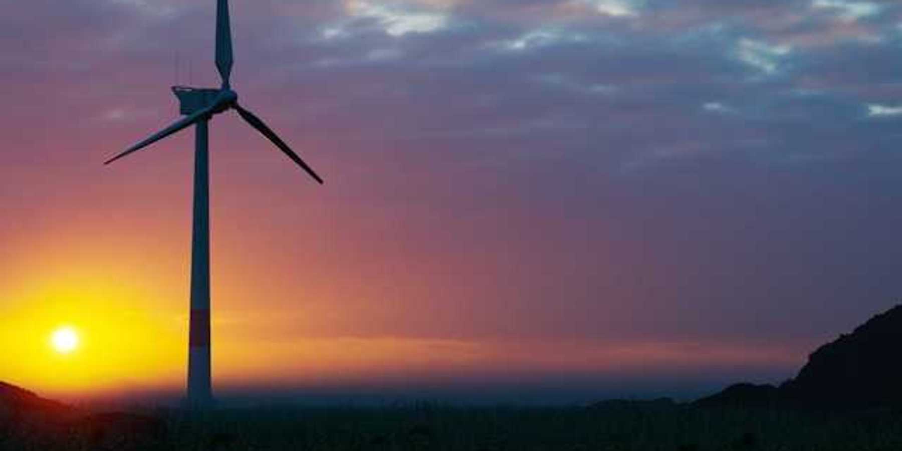 A wind turbine silhouetted against the setting sun