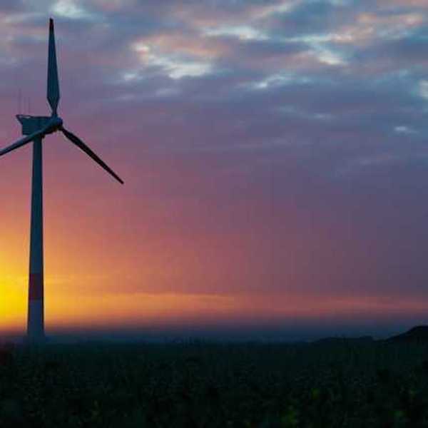 A wind turbine silhouetted against the setting sun