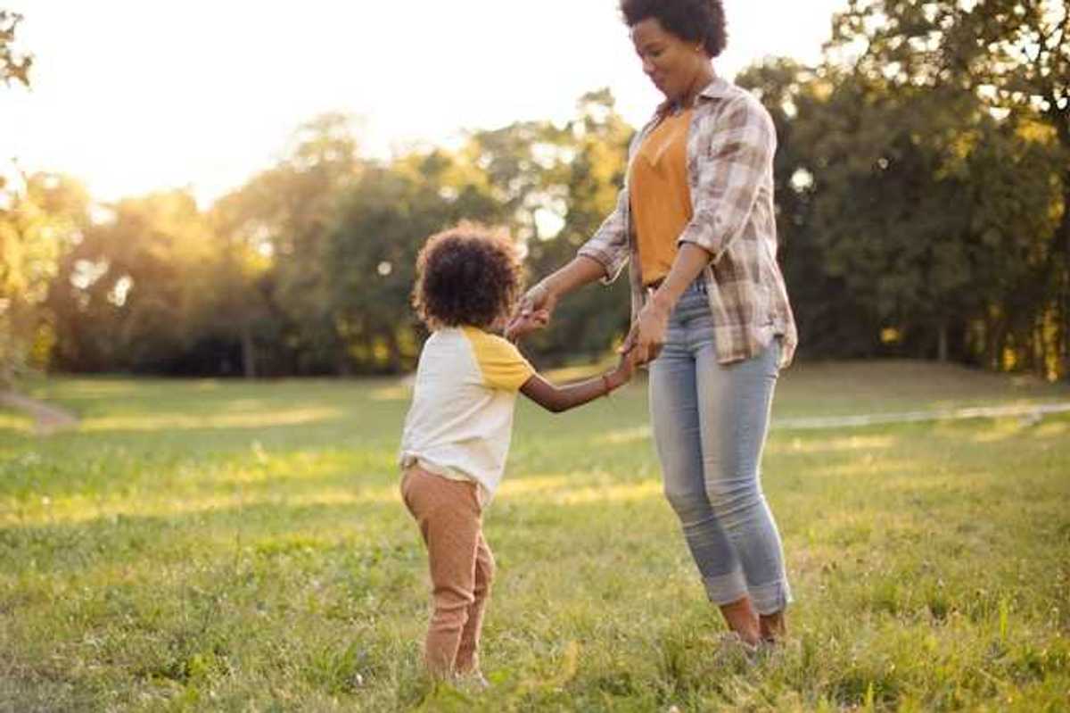 A woman and a child holding hands and dancing in a field