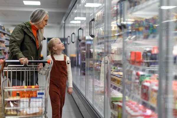 A woman and child standing in front of grocery store refrigerators