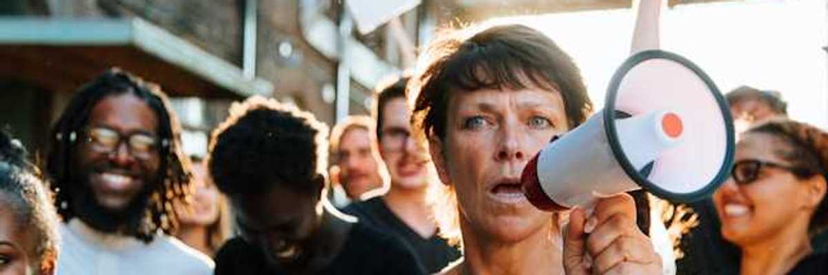 A woman at the front of a protest holding a microphone