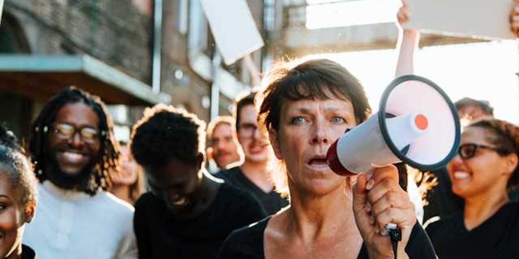 A woman at the front of a protest holding a microphone