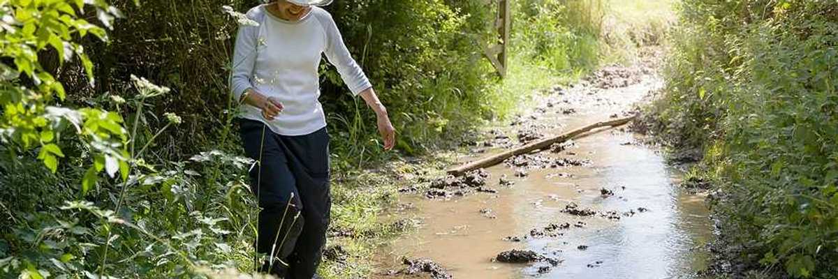 A woman hiking along a flooding stream