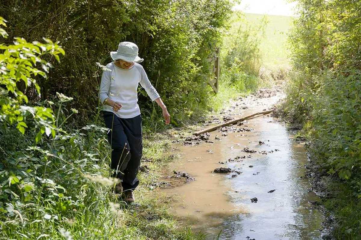 A woman hiking along a flooding stream