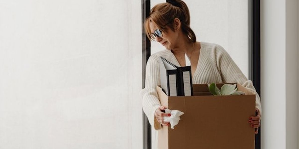 A woman holding a box with her office possessions after layoff.