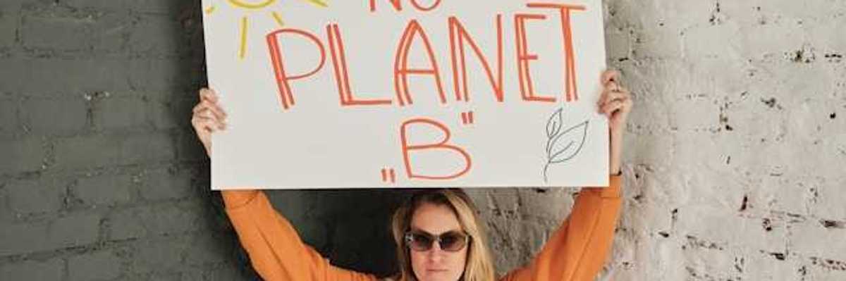 A woman holding a protest sign saying 'There is no planet B'
