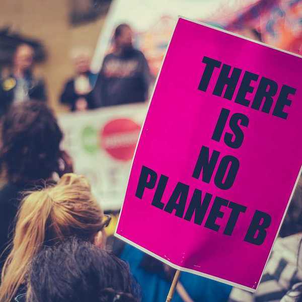 A woman holding a protest sign that says There is no planet B