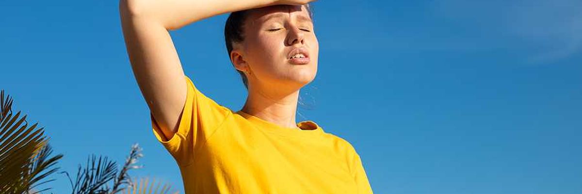 A woman holding her hand to her forehead on a hot day