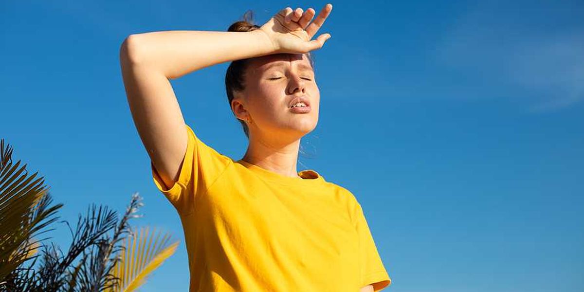 A woman holding her hand to her forehead on a hot day