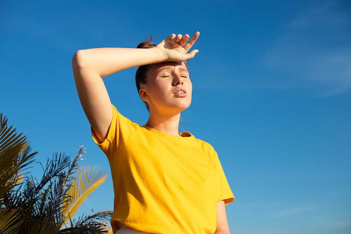 A woman holding her hand to her forehead on a hot day