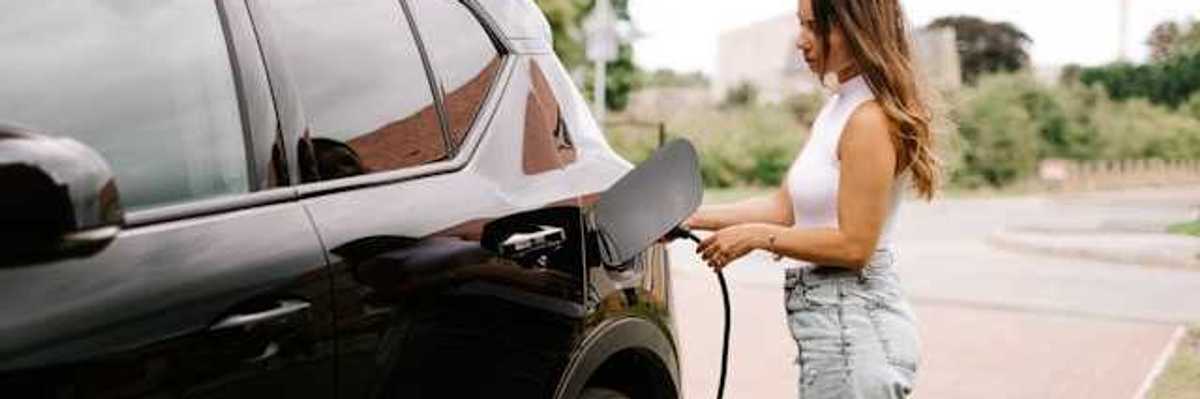 A woman hooking her electric vehicle up to a charger