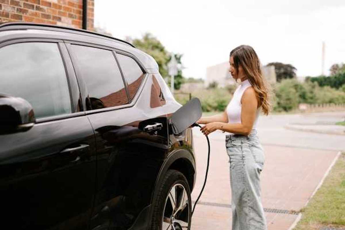 A woman hooking her electric vehicle up to a charger