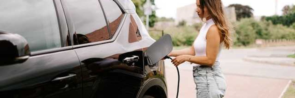 A woman inserting a charging cable into an electric vehicle