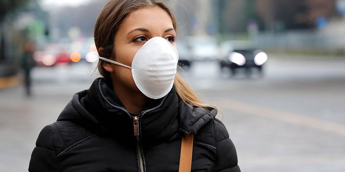 A woman on the street wearing a face mask.