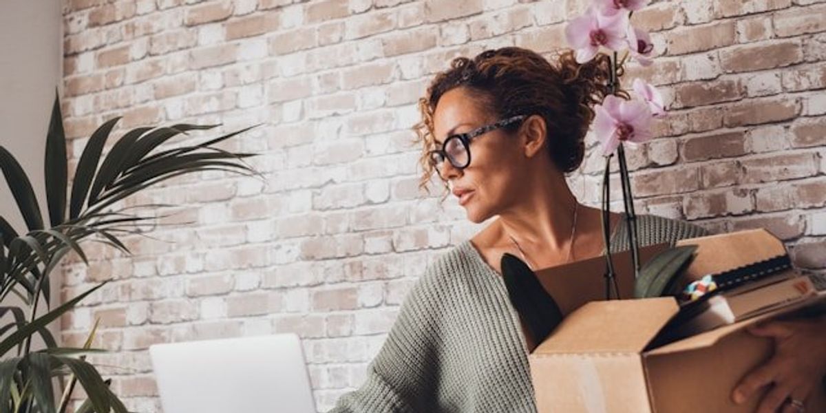 A woman packing up her office belongings in a cardboard box.