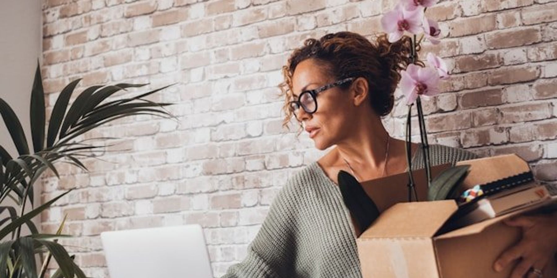 A woman packing up her office belongings in a cardboard box.