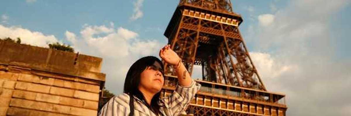 A woman shielding her eyes from the sun with the Eiffel Tower in the background