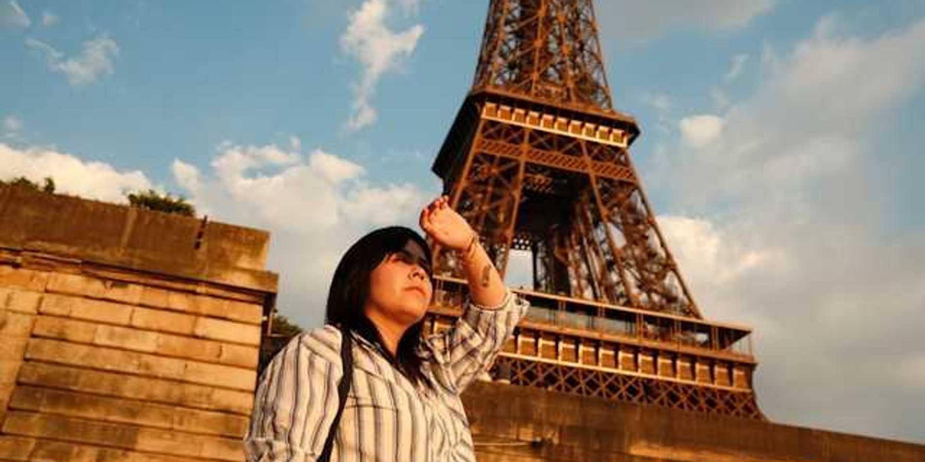 A woman shielding her eyes from the sun with the Eiffel Tower in the background
