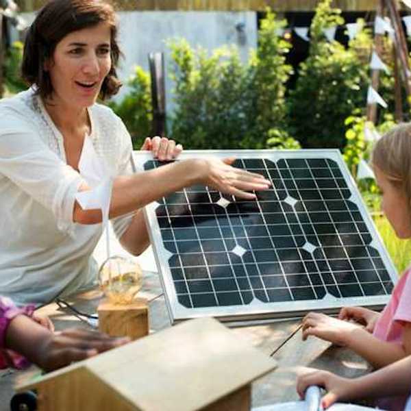 A woman showing a small solar panel to a group of children