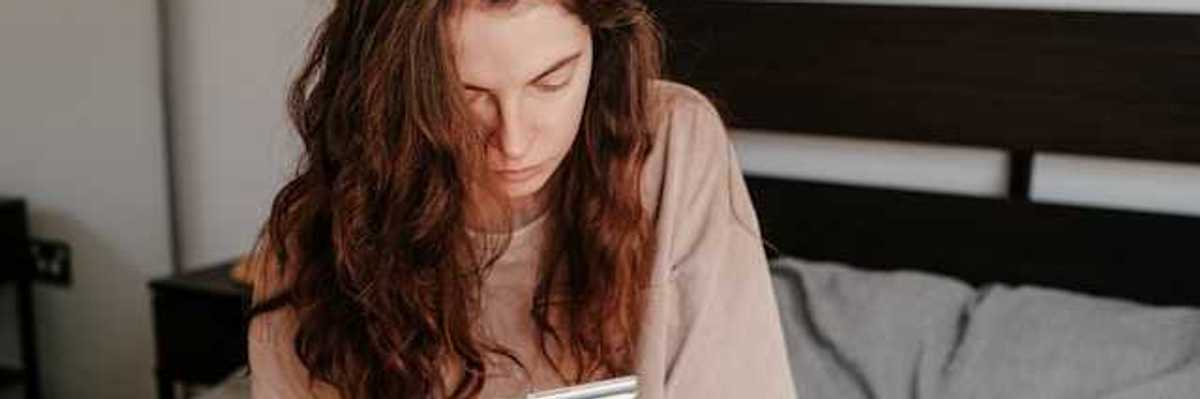 A woman sitting in bed looking at her phone