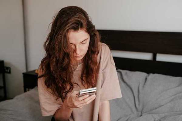 A woman sitting in bed looking at her phone