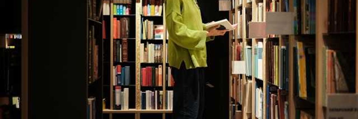 A woman standing on a stool in front of library bookshelves