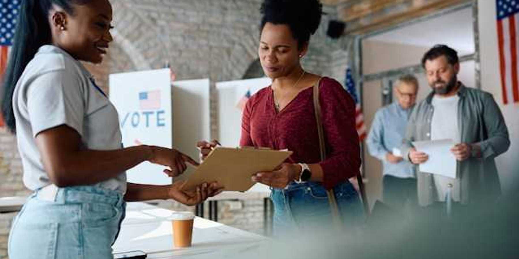 A woman talking to a voting representative at a polling station