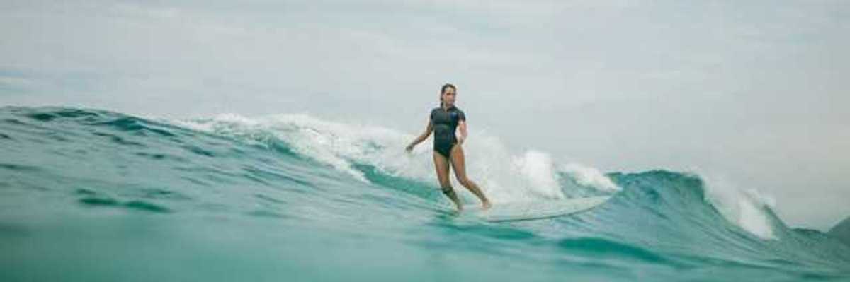 A woman wearing a wetsuit surfing a wave