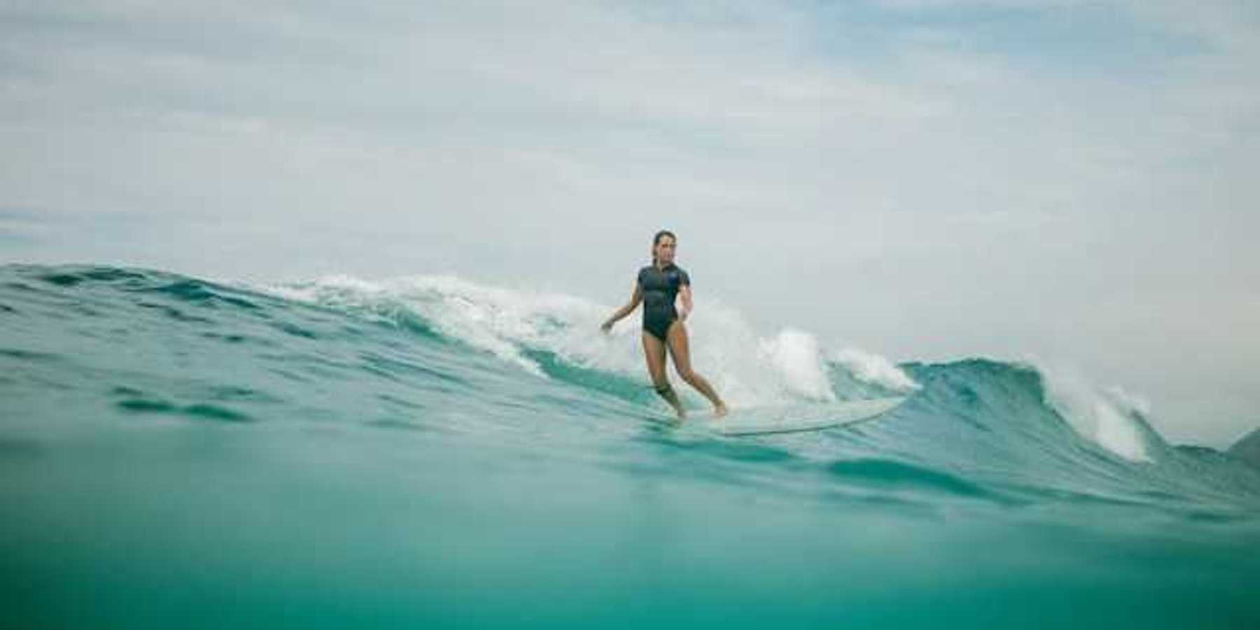 A woman wearing a wetsuit surfing a wave