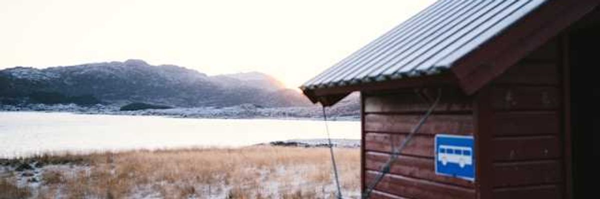 A wooden building in front of an icy landscape with water in the background