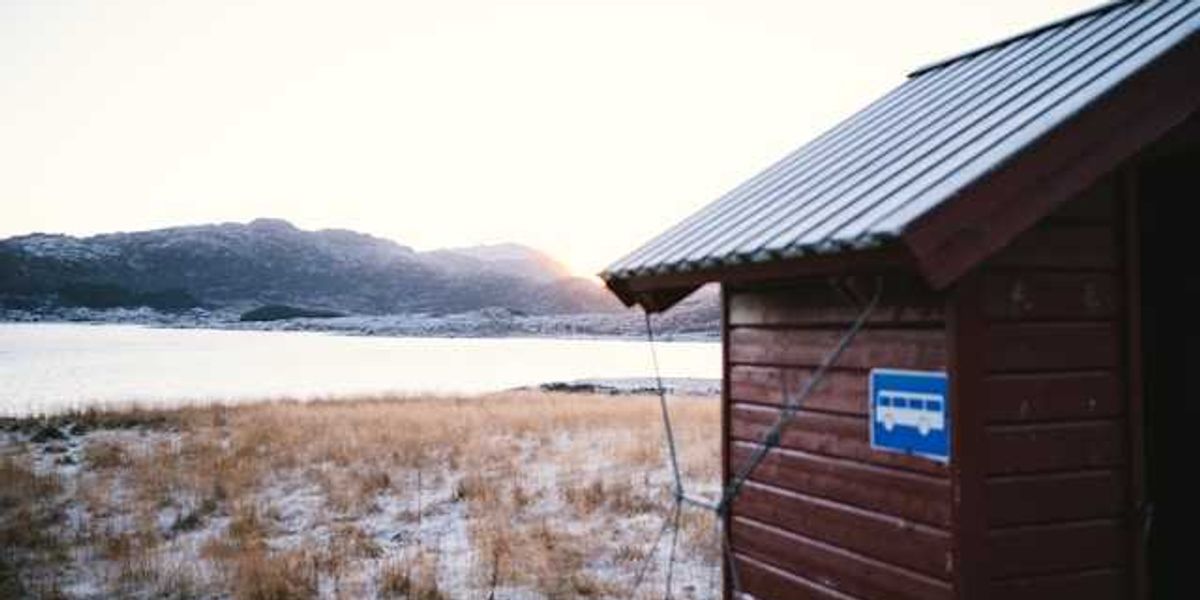 A wooden building in front of an icy landscape with water in the background