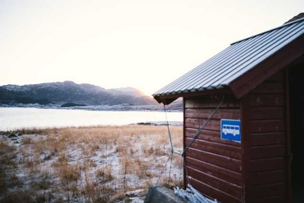 A wooden building in front of an icy landscape with water in the background