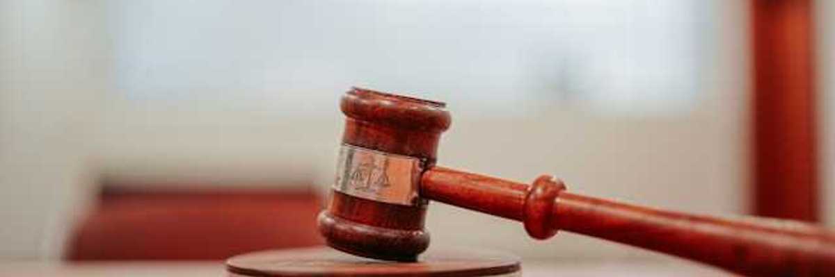 A wooden gavel resting on a round pedestal on top of a desk
