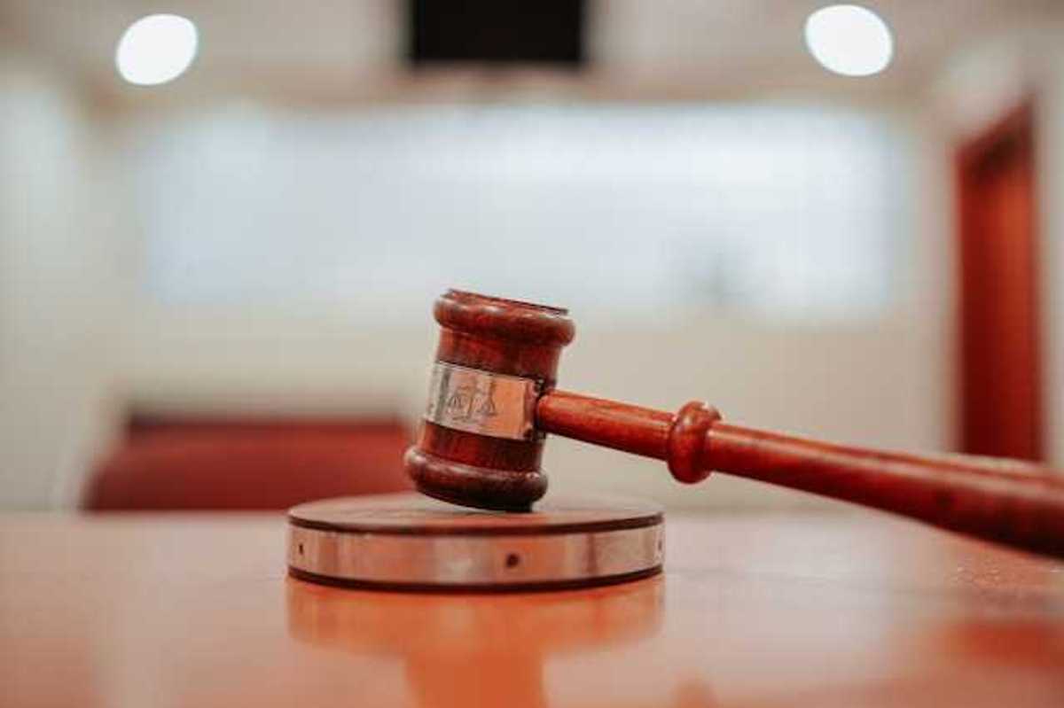 A wooden gavel resting on a round pedestal on top of a desk