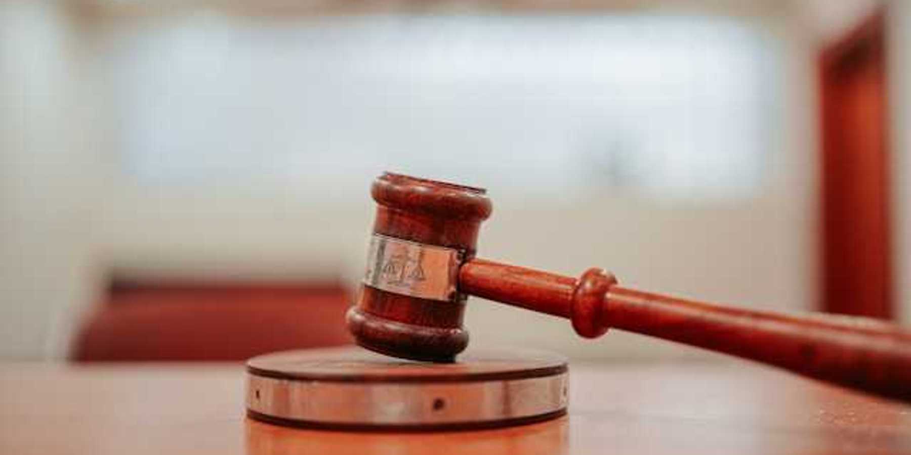 A wooden gavel resting on a round pedestal on top of a desk