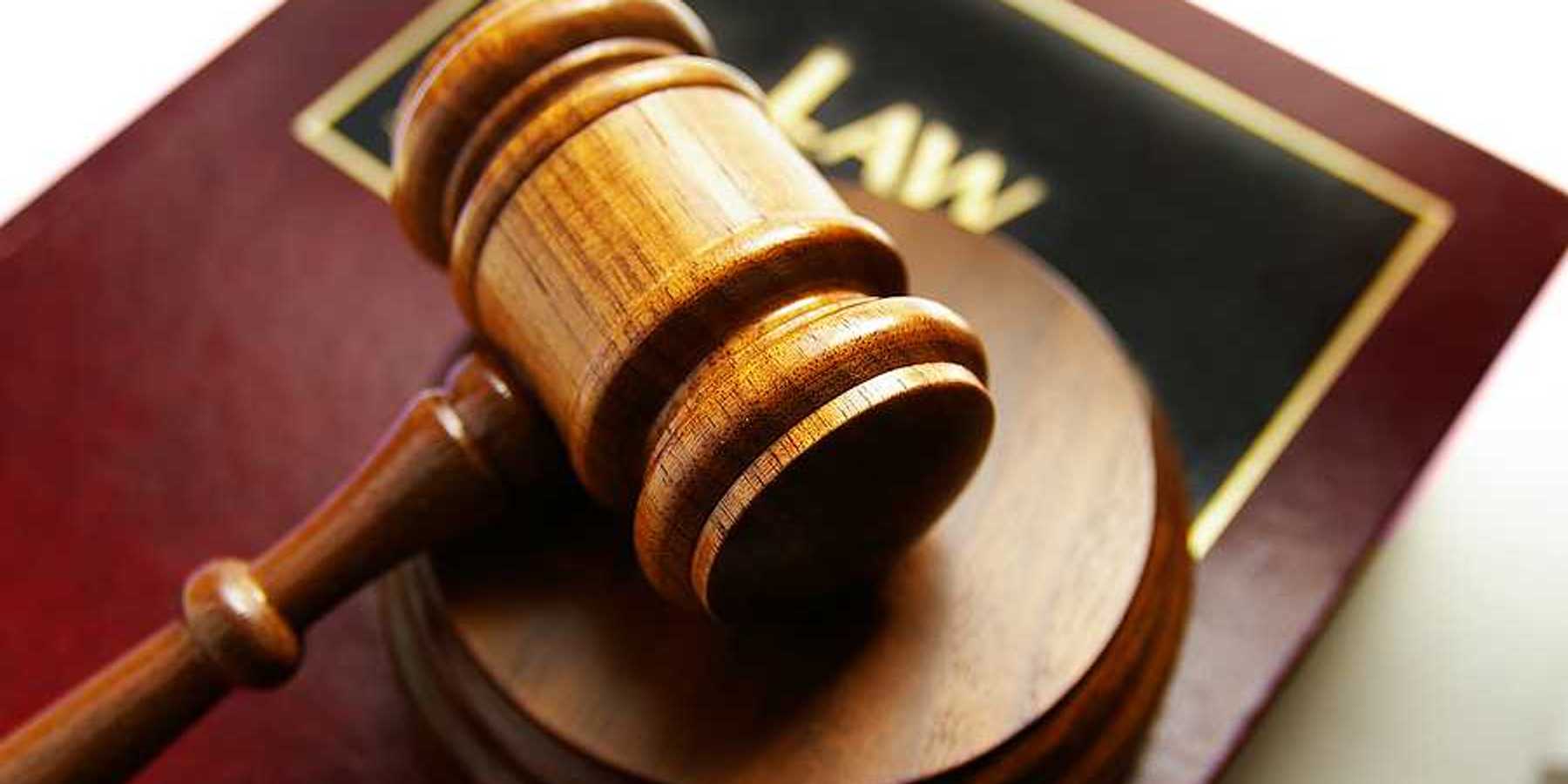 A wooden gavel sitting on top of a law book
