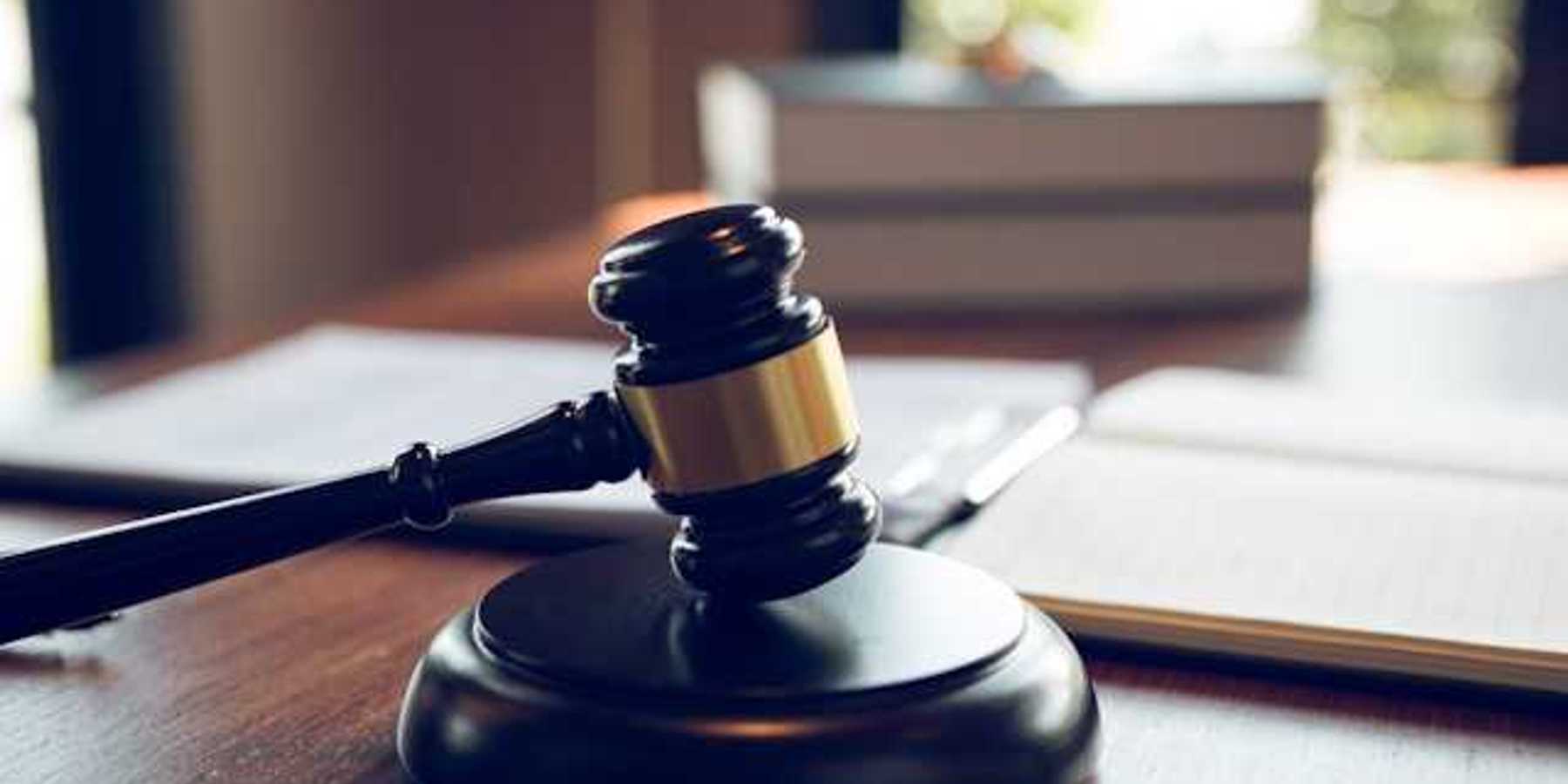 A wooden judge's gavel on a wooden desk