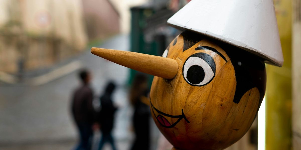 a wooden statue of pinocchio with a long nose and a white hat on its head