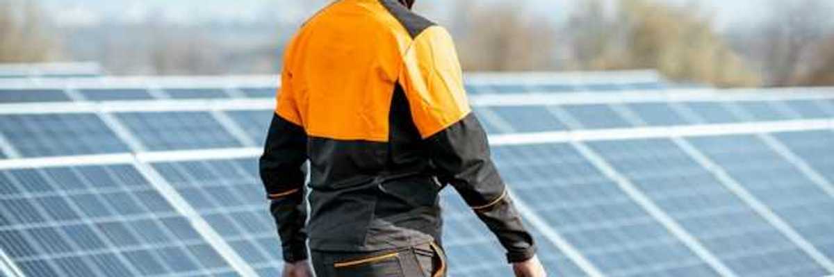 A worker in an orange hard hat inspecting solar polars