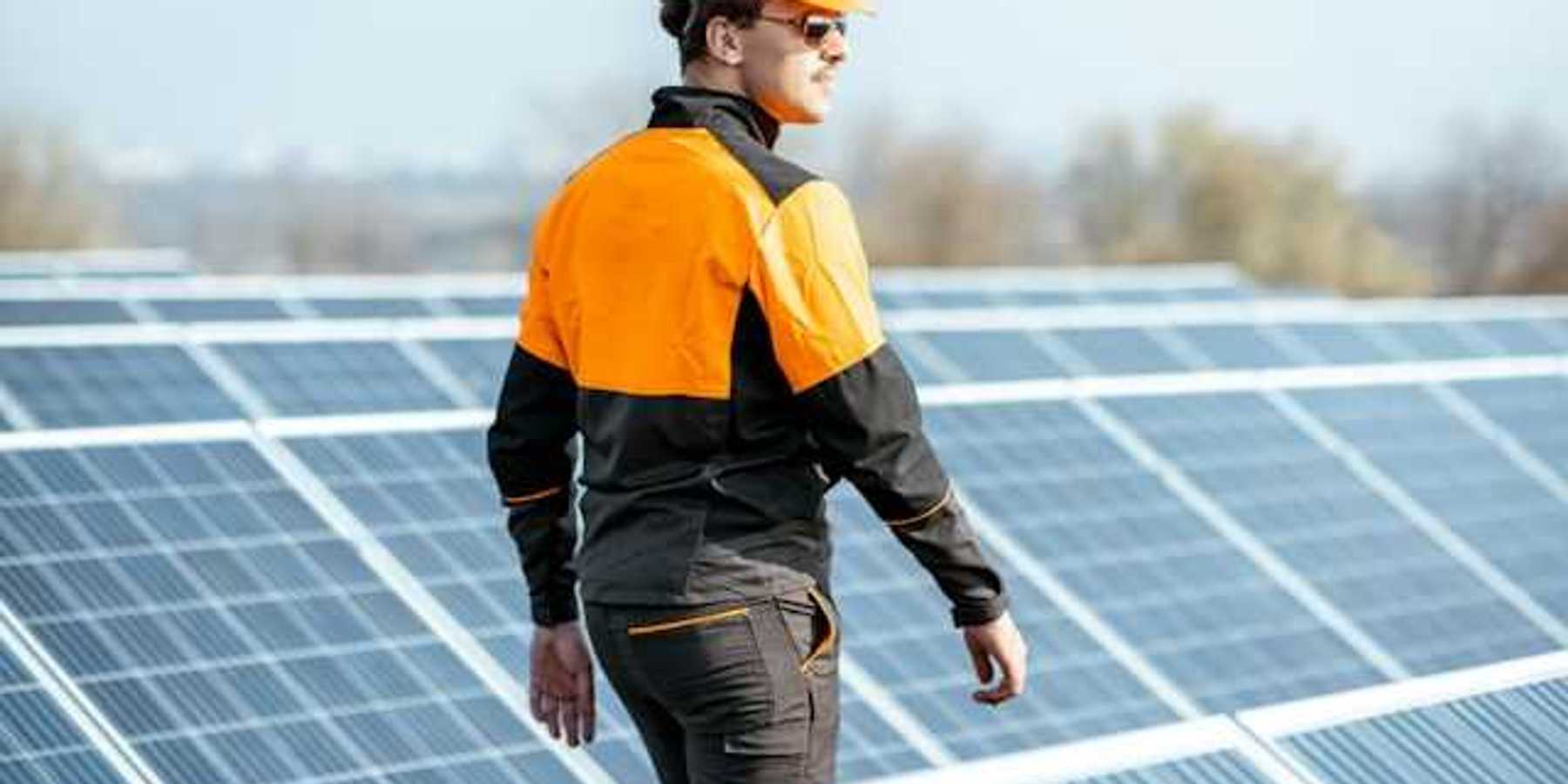 A worker in an orange hard hat inspecting solar polars