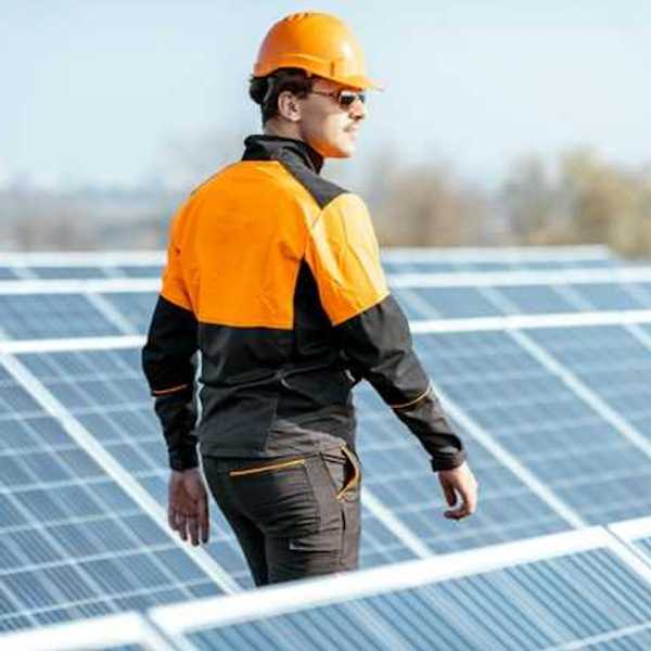 A worker in an orange hard hat inspecting solar polars