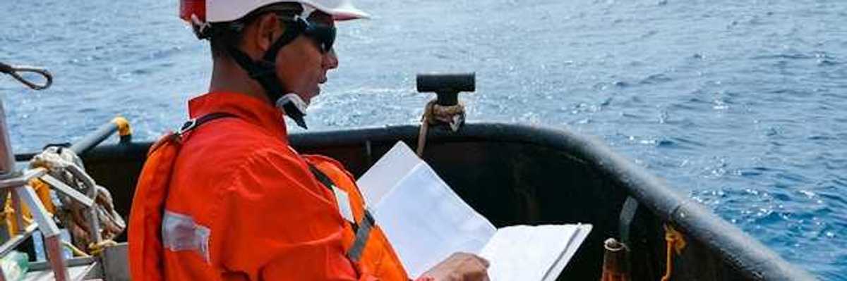 A worker in an orange jumpsuit and hardhat on an oil drill